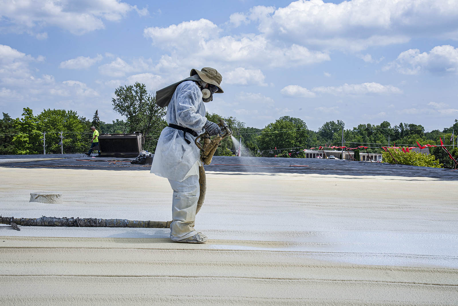 person applying silicone coating to spf spray foam roof coating