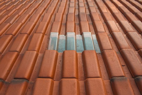 How to Choose the Right Roofing Contractor - A close up shot of rust-colored roofing material with a silver-colored rectangle in the center. Commercial Roof Leaks.