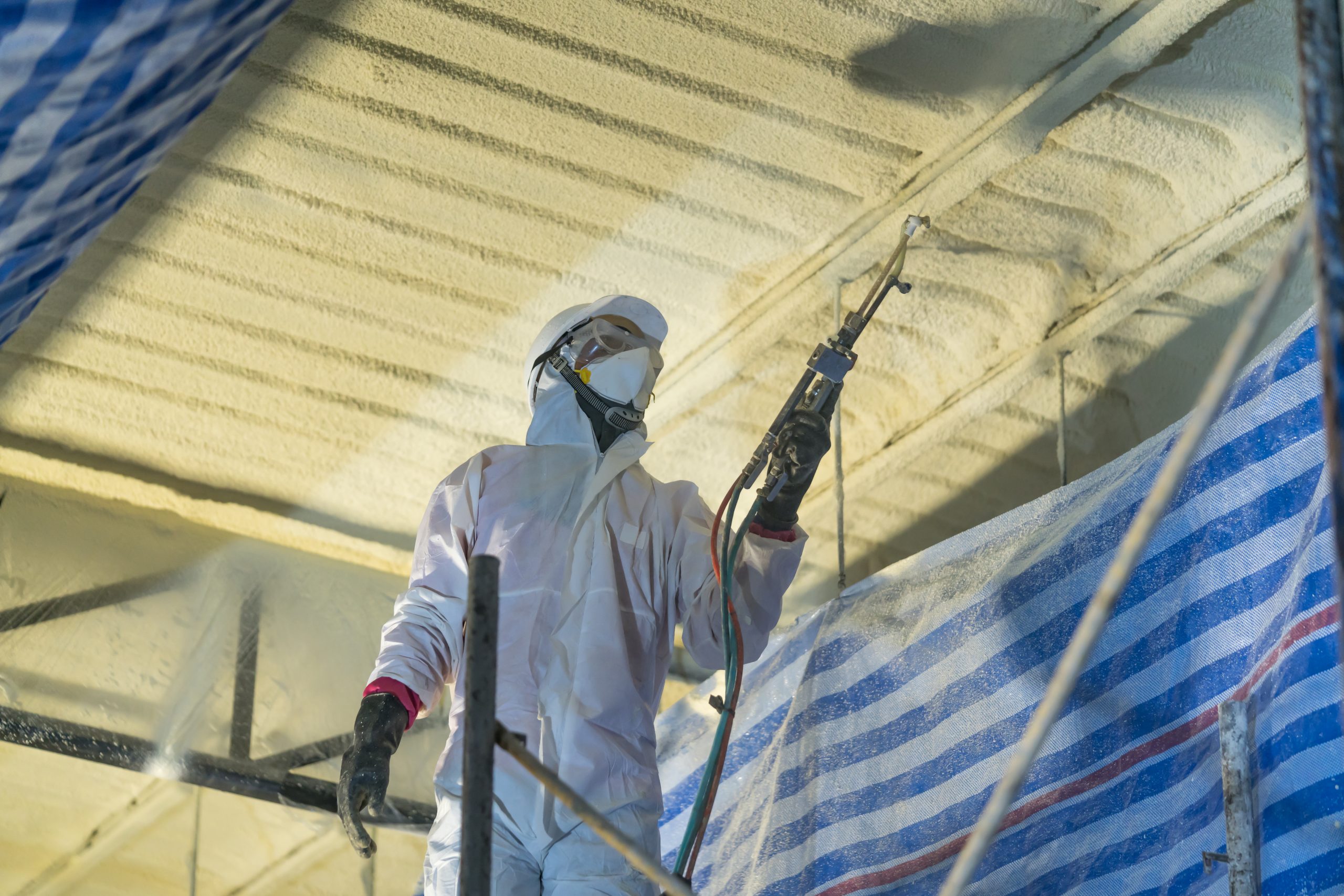 Spray Foam Roofing Technician spraying foam insulation using Plural Component Gun for polyurethane foam