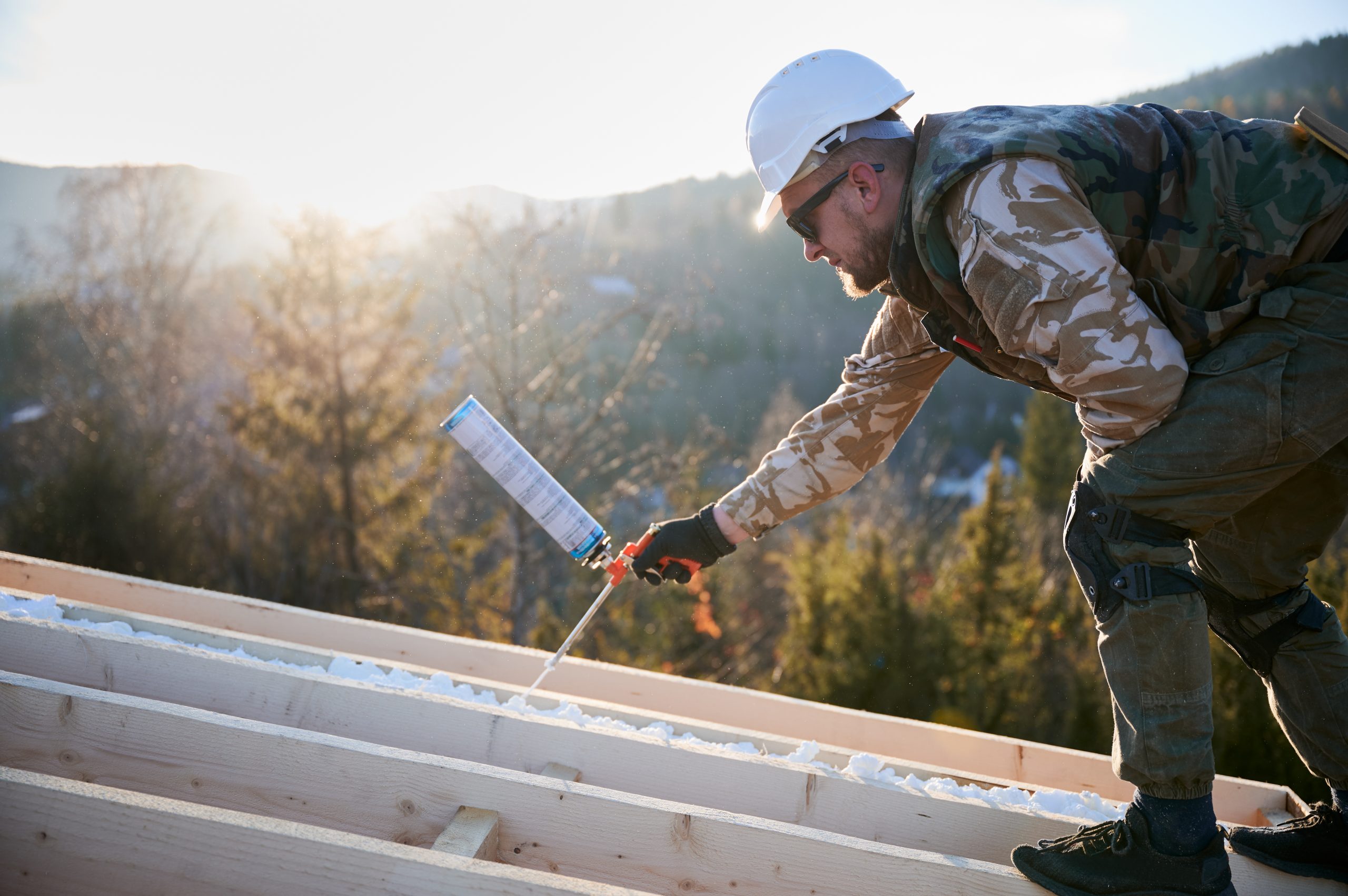 spray foam cost vs. benefit: guy on roof using SPF