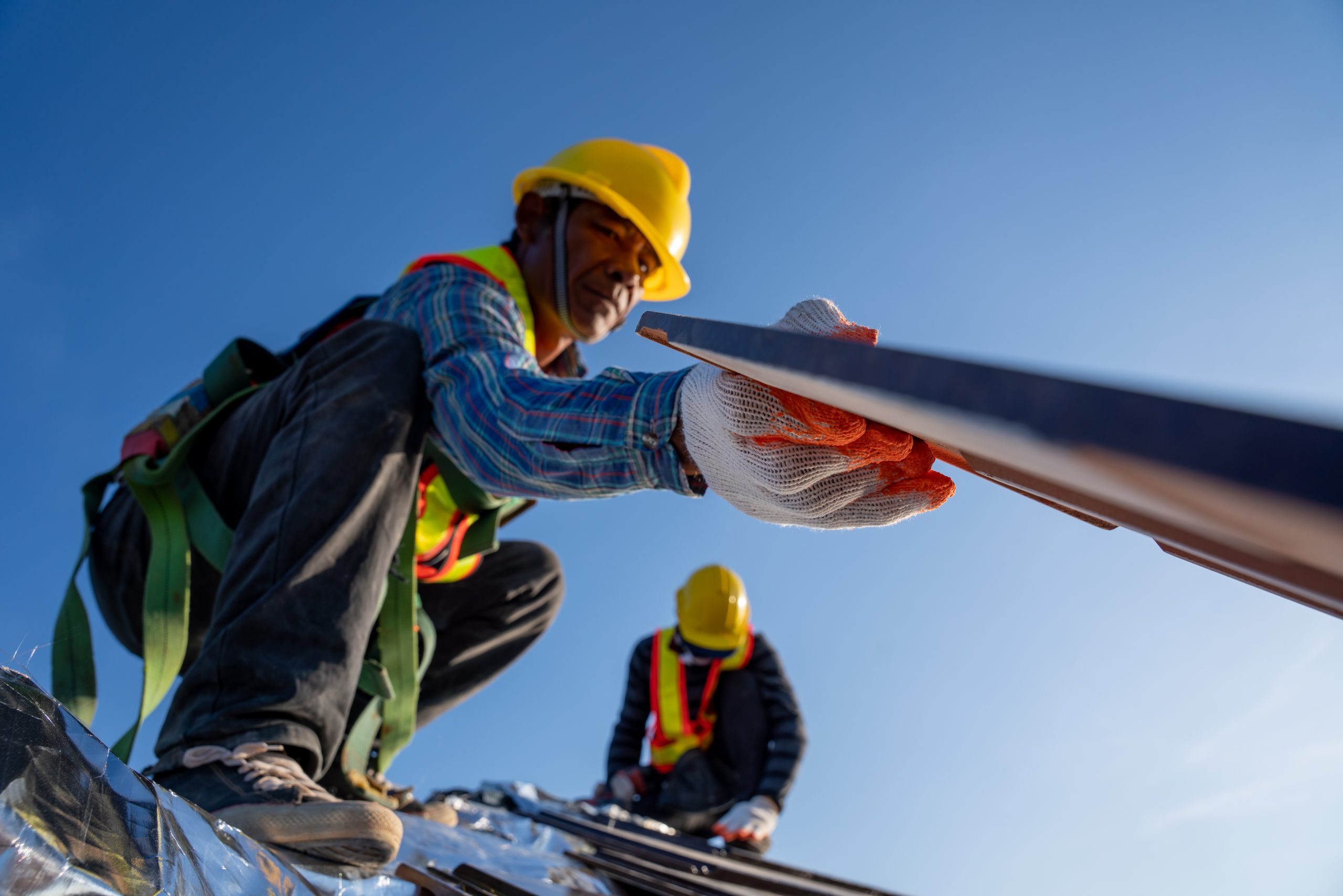 commercial roofing pros and cons male worker picking up piece of roof